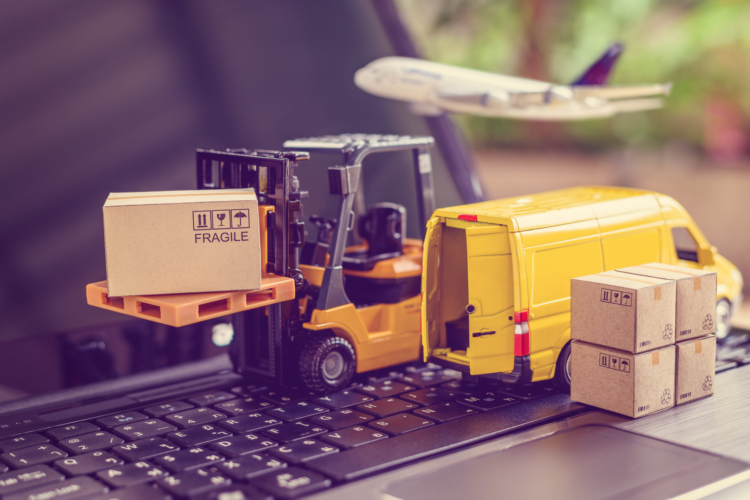 Logistics, supply chain and delivery service concept : Fork-lift truck moves a pallet with box carton. Van on a laptop computer, depicts wide spread of products around globe in ecommerce popular era