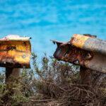 Rusty broken guardrail with yellow paint on a cliff