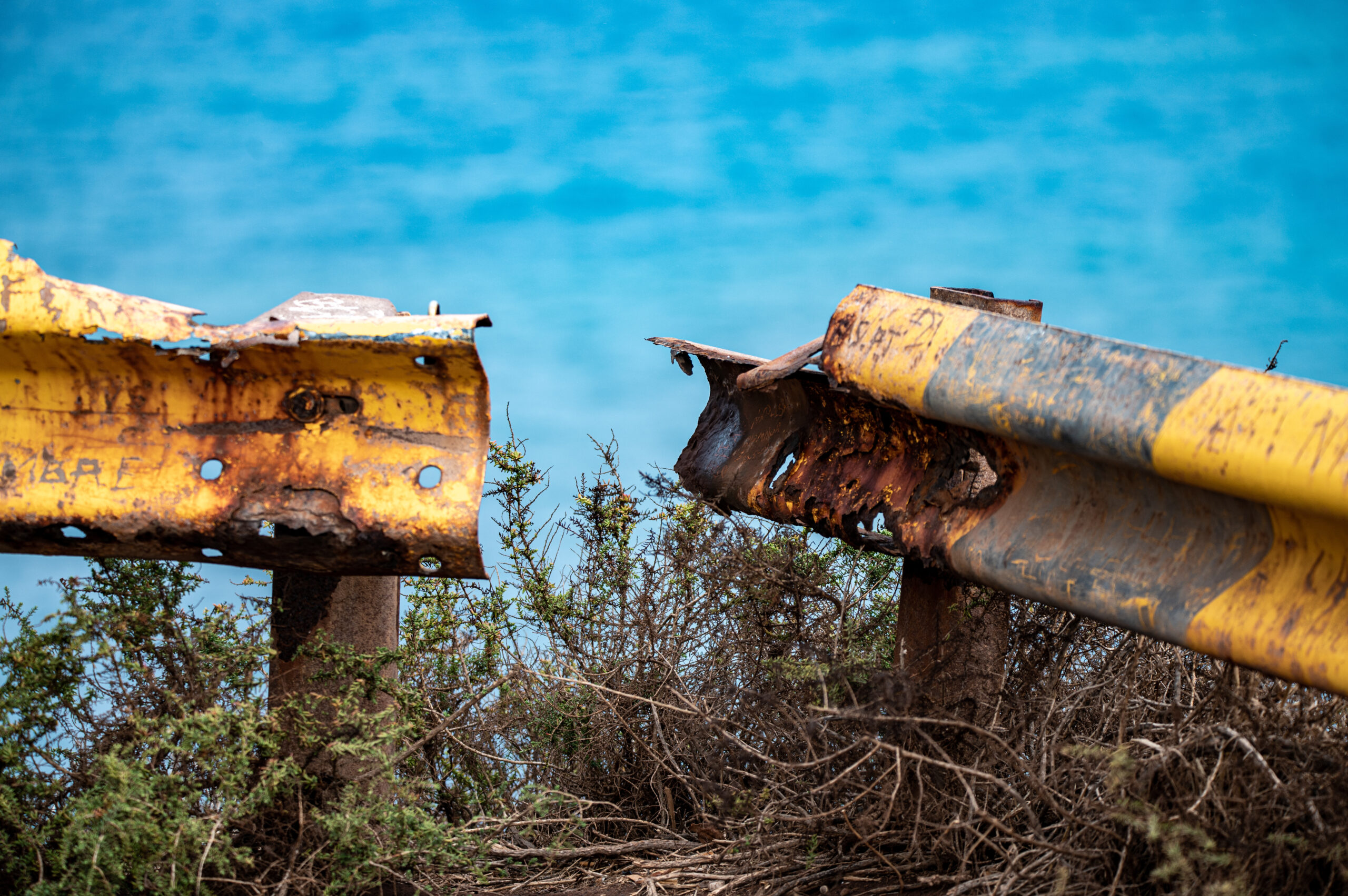 Rusty broken guardrail with yellow paint on a cliff