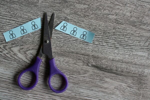 Scissor cut paper with employee icon. Mass layoffs, downsizing concept.
