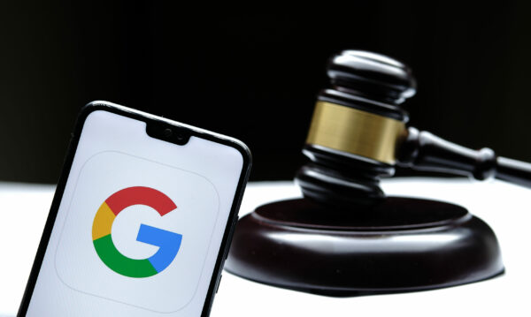 Google logo seen on the smartphone placed next to the judges gavel. Concept for a lawsuit, legal case, antitrust and fine. Real photo, not a montage. Stafford, United Kingdom - December 15 2020.