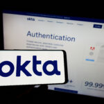 Stuttgart, Germany - 03-29-2022: Person holding cellphone with logo of US identity management company Okta Inc. on screen in front of business webpage. Focus on phone display.