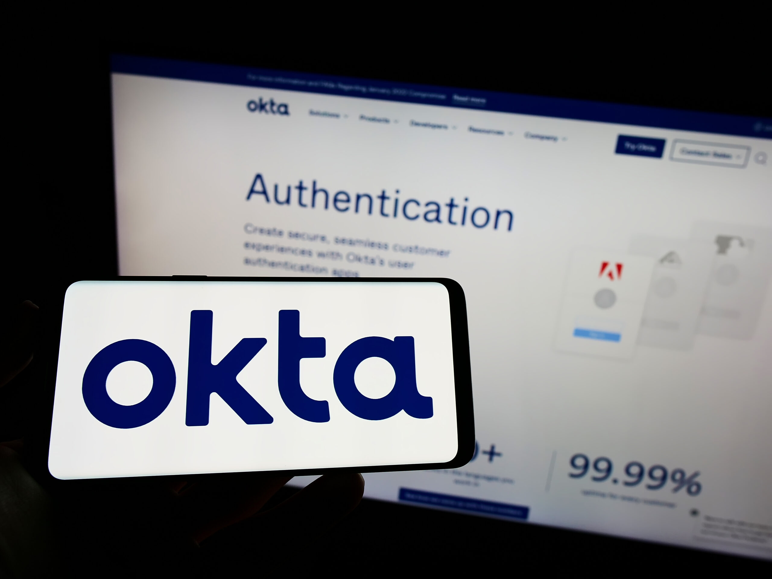 Stuttgart, Germany - 03-29-2022: Person holding cellphone with logo of US identity management company Okta Inc. on screen in front of business webpage. Focus on phone display.