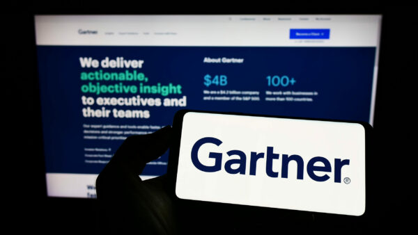 Stuttgart, Germany - 07-30-2022: Person holding mobile phone with logo of American research company Gartner Inc. on screen in front of business web page. Focus on phone display.