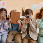 Group of young children holding smartphones and hiding faces