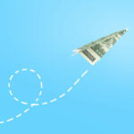 Dollar paper airplane on blue background