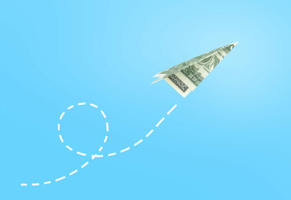 Dollar paper airplane on blue background