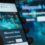 Microsoft Mesh a new mixed-reality platform on smartphone display. VR headset at background. VR an AR with Microsoft Mesh crossplatform environment. Moscow 3 March 2021