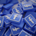 The image shows a collection of three-dimensional Facebook "f" logo icons in blue and white. The icons are scattered and piled up, with some facing upwards and others at various angles, creating a sense that there are numerous such icons in the image. The "f" is the well-known logo of Facebook, a popular social media platform. The colors are consistent with the Facebook brand's color scheme.