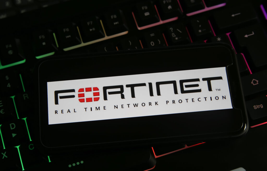 Closeup of mobile phone with logo lettering of fortinet anti virus computer network security software on keyboard