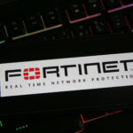 Closeup of mobile phone with logo lettering of fortinet anti virus computer network security software on keyboard