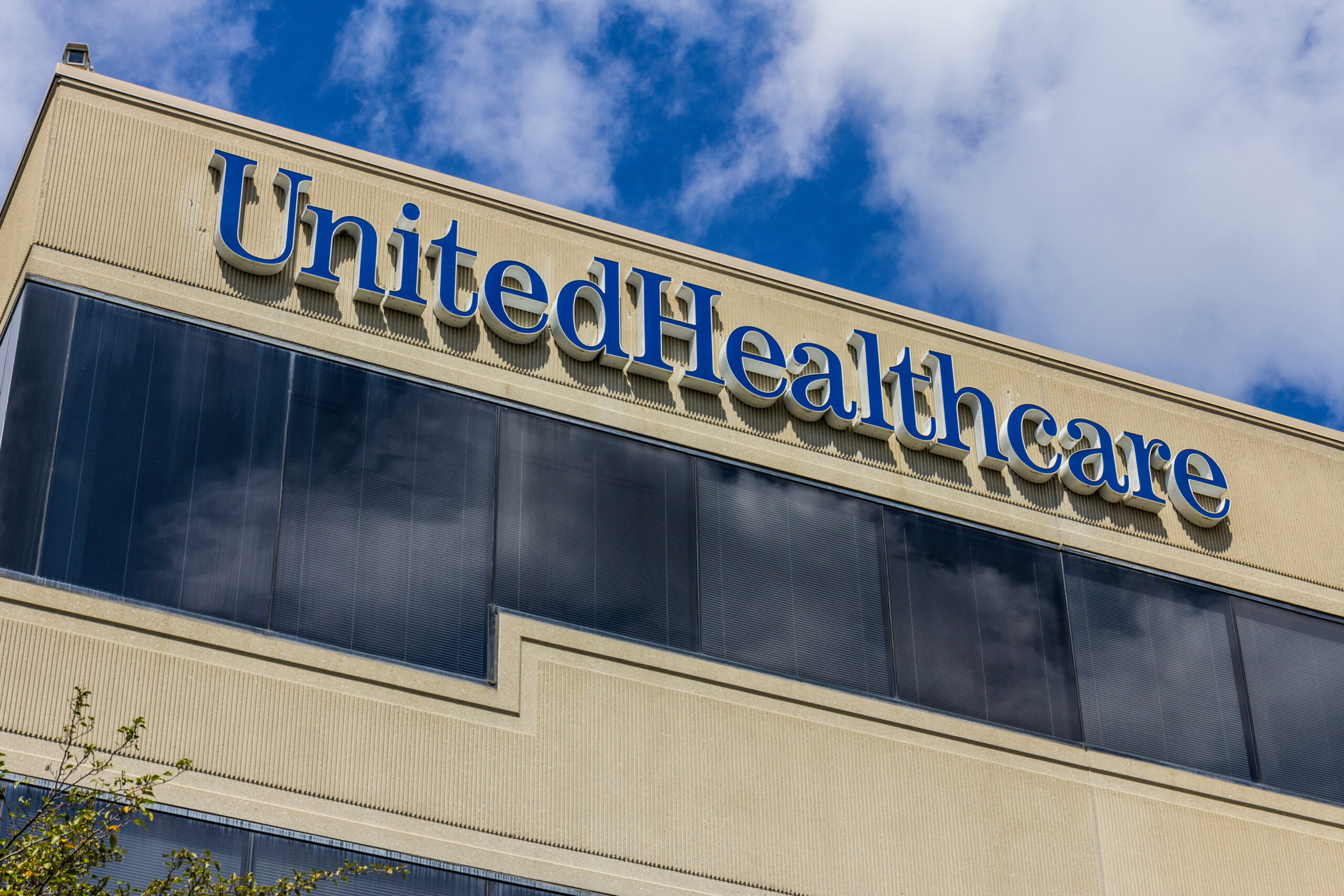 The image is of a building with a sign that reads "UnitedHealthcare." The UnitedHealthcare logo is in a bold, blue font, which stands out against the cream-colored background of the building's facade.