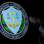 FTC Federal Trade Commission of the United States of America logo seen on the display in a dark room and blurred finger pointing at it.