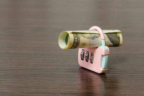 Rolled up cash in a lock, suggesting locked funds or blocked payment.