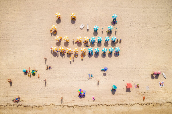 Top view of beach with colorful umbrellas and people bathing in the sun in South Beach Miami, Florida, USA.