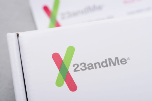23andMe logo closeup on personal genetic test saliva collection kit. Illustrative editorial.