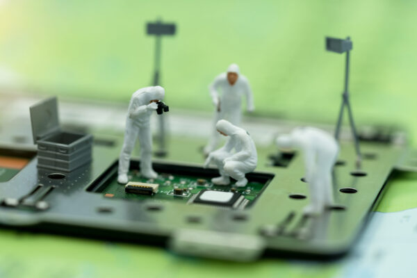 Miniature people searching for bugs on microchip.