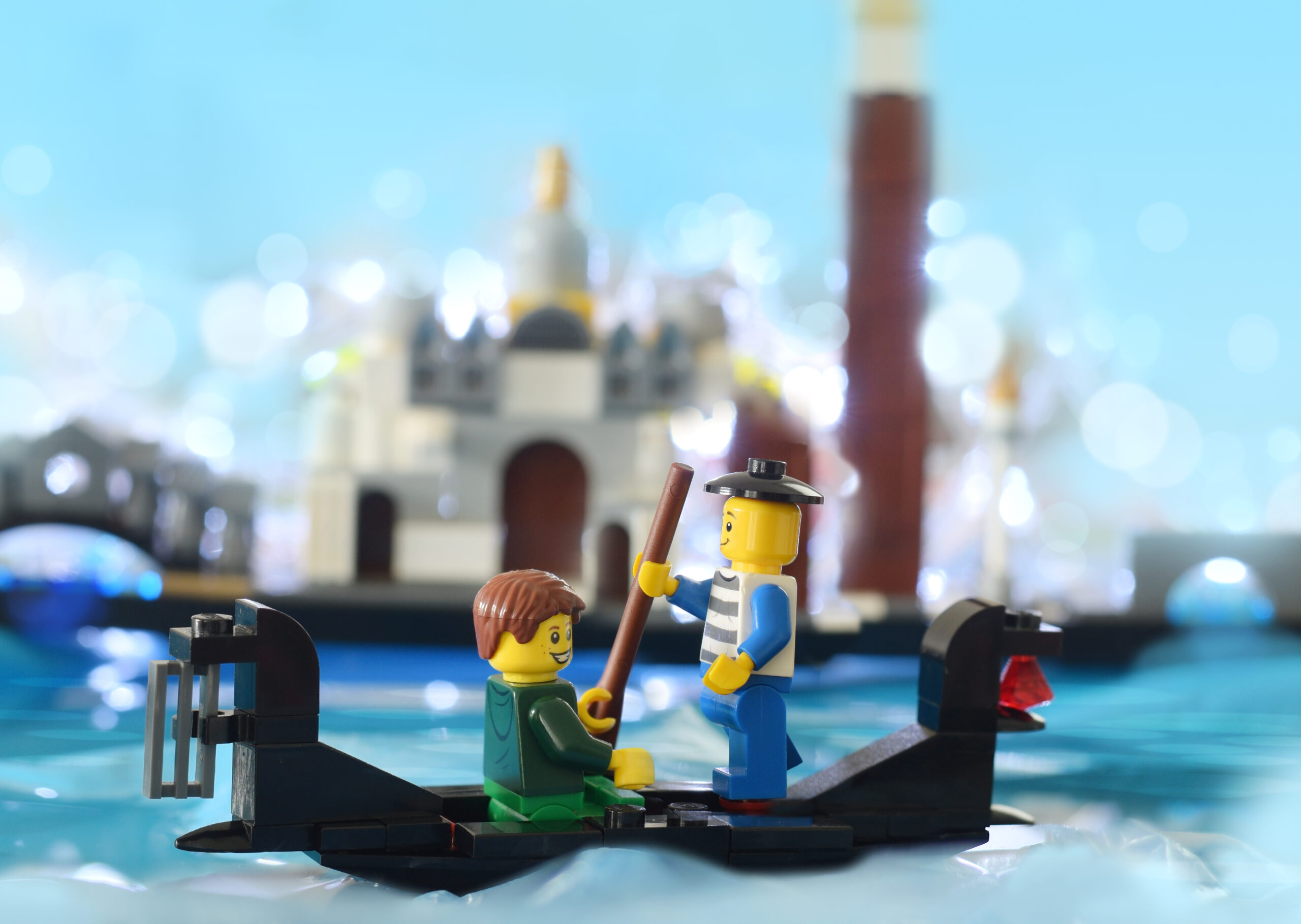 Editorial illustrative image of lego minifigure is boating on water in gondola in Venice. Studio shot of popular travel place and plastic toys.