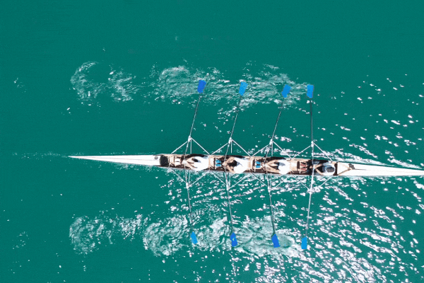 Aerial drone top down video of sport canoe operated by team of young women in emerald clear waters