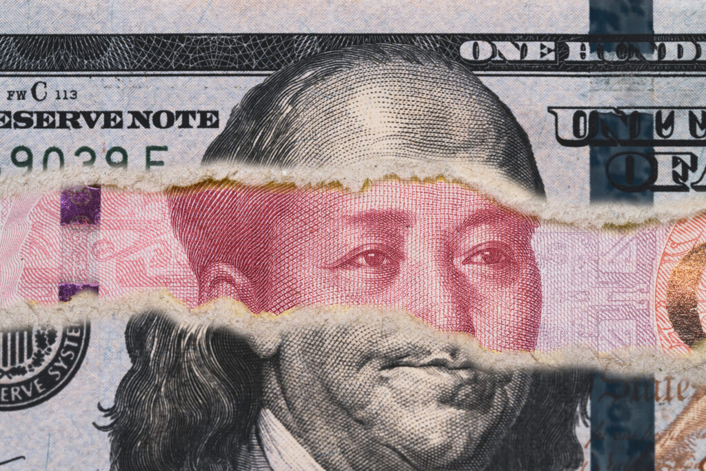 Benjamin Franklin on USD dollar banknote tear with Mao Tse Tung on Yuan banknote.