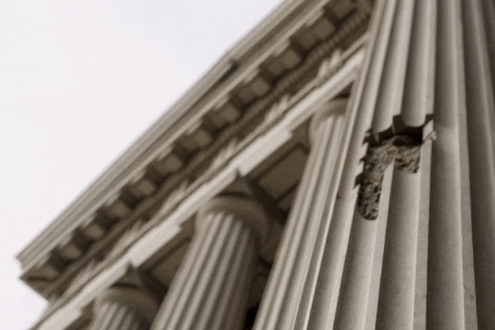 A grand federal courthouse with one cracked column crumbling at the base.