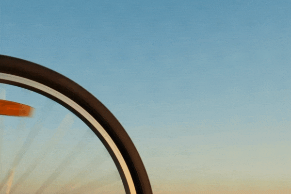 The wheel of a bicycle. A spinning bicycle wheel against the sky.