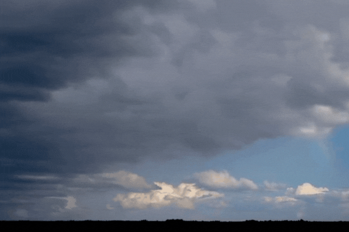 A dark storm cloud dissolves into clear blue, with a rainbow bridging the divide.