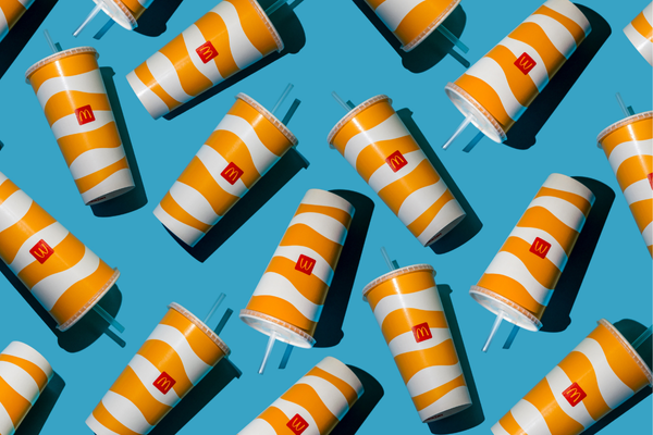 Yellow glass of McDonald's. Paper cup with lid. Takeaway drink. McDonald's logo. McCafe cup shadow top view pattern. Orange juice Fanta drink. Fastfood background. Ukraine, Kyiv - October 6, 2023.