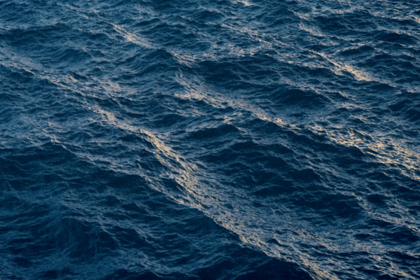 Fly over ocean water surface in evening time