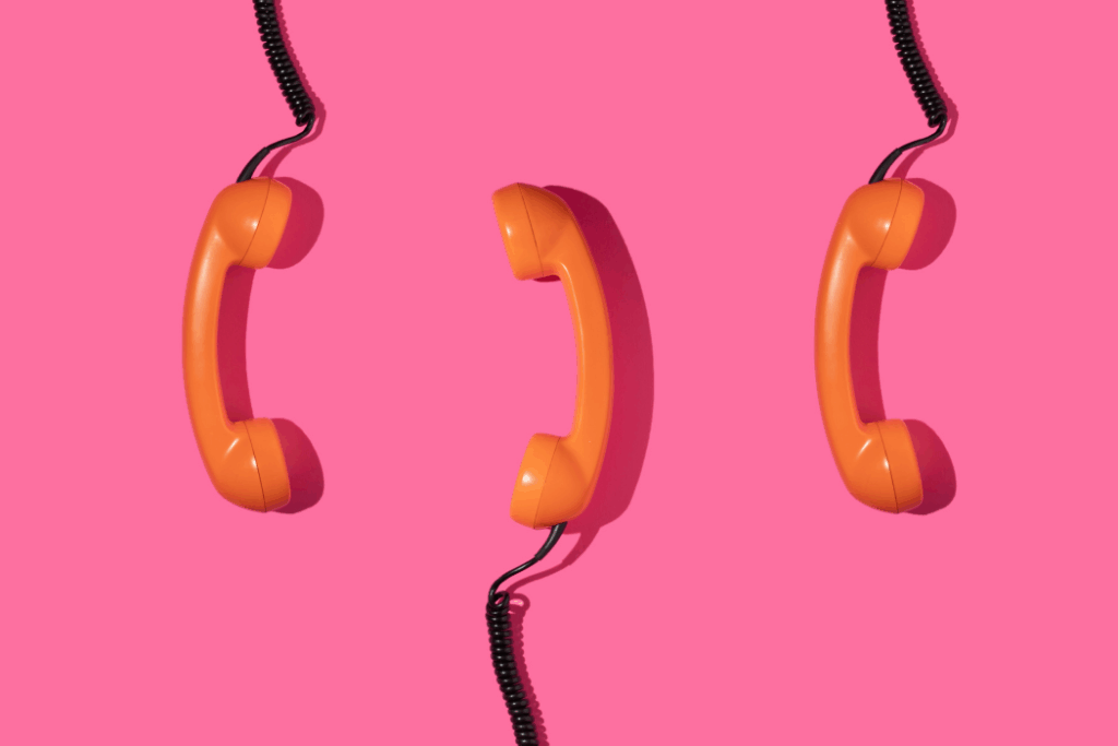 Old phone handsets on bright pink background