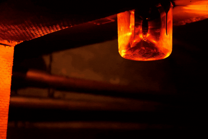 Close-up of a rotating red emergency siren lamp on the wall of a dark tunnel.