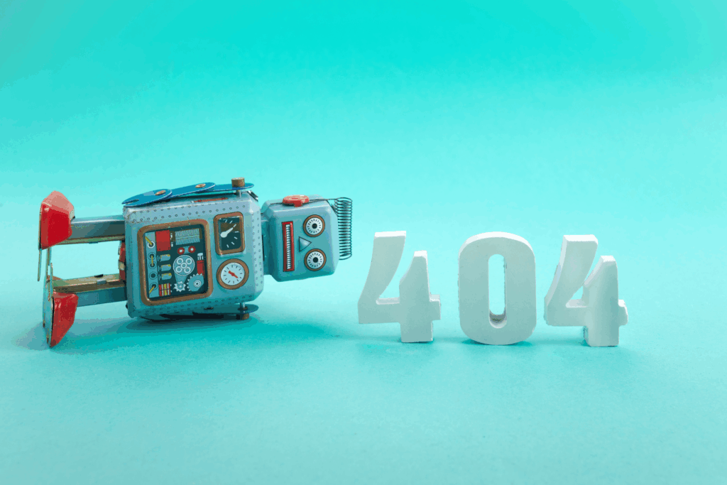 A retro toy robot lies beside large white “404” numbers against a bright turquoise background.