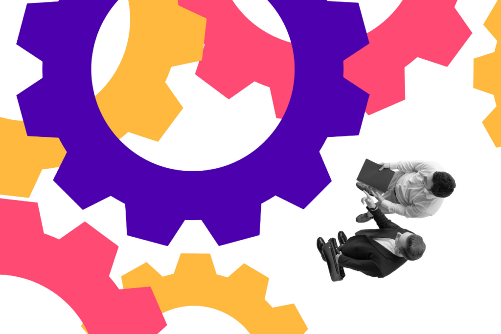 Two businessmen shaking hands while standing near large colorful gears